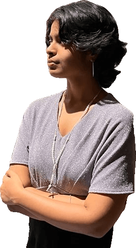Riya in a lavender top, arms folded, looking away