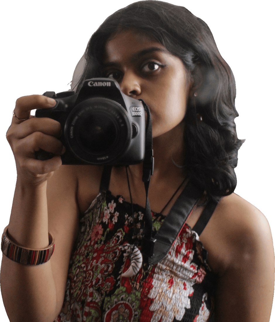 Riya holding a Canon camera up to her face, mid-shot